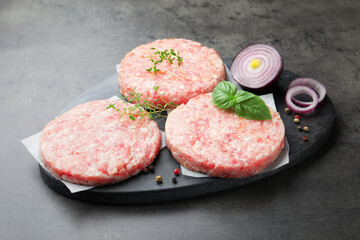 Fresh raw patties for burger and spices on grey table, closeup