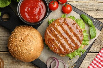 Delicious hamburger patty, bun, vegetables and spices on wooden table, flat lay