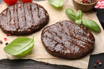 Delicious hamburger patties and spices on wooden table, closeup