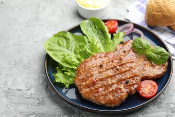 Delicious hamburger patties, tomato, lettuce, buns and spices on grey table, closeup. Space for text
