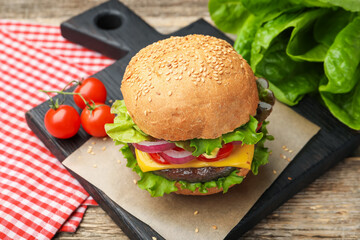 Delicious hamburger with patty and cheese on wooden table, closeup