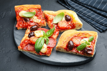 Pieces of tasty homemade pizza on black table, closeup