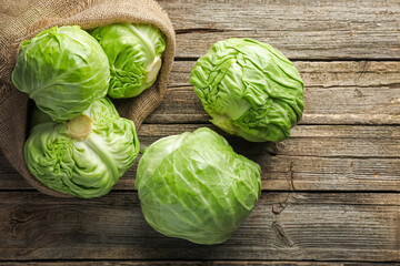 Fresh whole cabbages on wooden table, flat lay