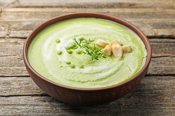 Tasty pea cream soup with croutons and thyme on wooden table, closeup