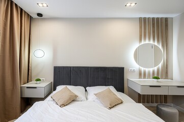 Modern bedroom with neutral tones. Features a bed with a gray headboard, white bedding, floating...