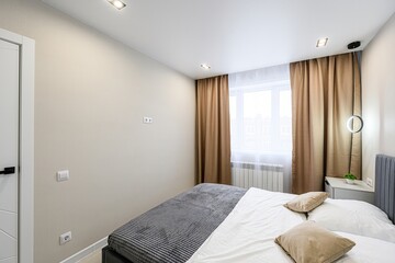 modern bedroom featuring a bed with a gray headboard, white linens, brown curtains, and a round,...