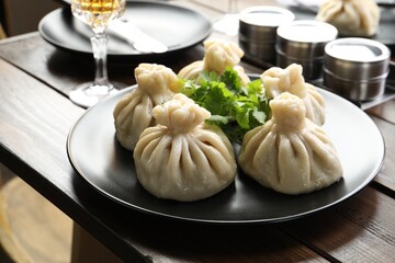 Delicious khinkali served with cilantro on wooden table, closeup