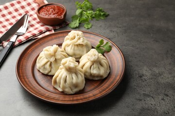 Delicious khinkali served with sauce on grey table, closeup