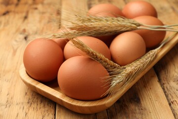 Fresh eggs and spikes on wooden table, closeup
