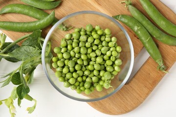 Fresh ripe green peas on white wooden table, flat lay