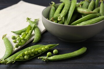Fresh ripe green peas on black wooden table, closeup
