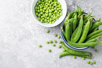 Fresh ripe green peas on grey table, flat lay. Space for text