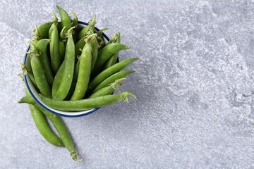 Fresh ripe green peas on grey table, top view. Space for text