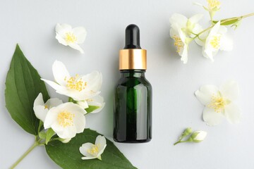 Cosmetic product and jasmine flowers on light background, flat lay