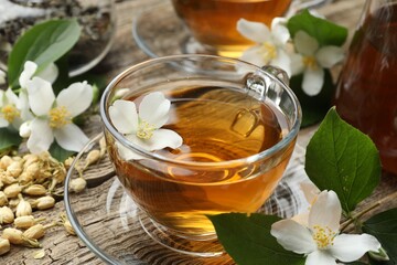 Aromatic jasmine tea in glass cups, brew and flowers on wooden table, closeup