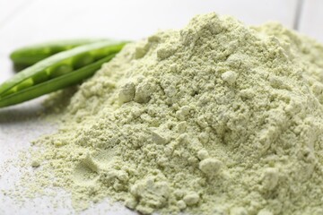 Protein powder and green peas on light tiled table, closeup