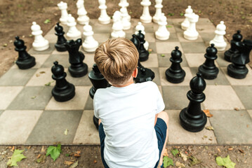 A child is playing big garden chess