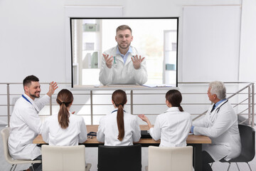 Team of doctors using video projector during conference indoors. Speaker on projection screen