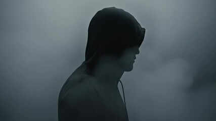 Enigmatic silhouette in fog, hooded figure standing mysterious dark in foggy backdrop - Powered by Adobe