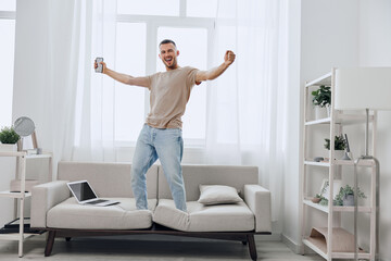 Happy man celebrating a breakthrough during a digital detox at home, balancing work and personal...