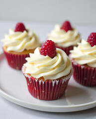 delicious raspberry-topped vanilla cupcakes with creamy frosting on a white plate