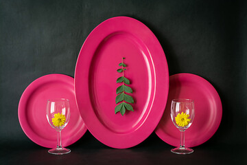 Image of a dinner set against dark background shot in window light. Pink Set of oval plates, round...