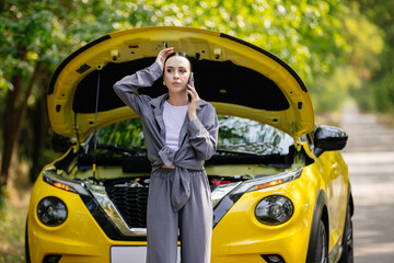 An agitated woman calls for help on the phone near a broken down new car on the street. Concerned...