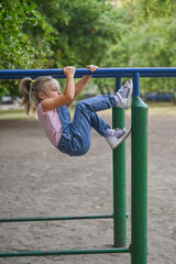 Fototapeta premium A little girl in a jumpsuit on a sports field