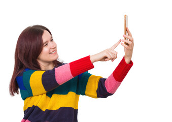 Positive young woman wearing colorful sweater pointing finger to her phone to take a photo. Joyful carefree female taking a selfie isolated on transparent background