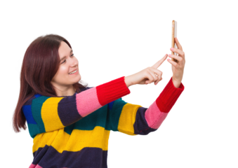Positive young woman wearing colorful sweater pointing finger to her phone to take a photo. Joyful carefree female taking a selfie isolated on transparent background