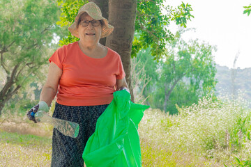 Senior woman volunteer collecting trash in forest using plastic bag