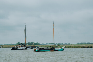 Plattbodenschiffe auf dem Weg zur Regatta, Die Mannschaften bereitet das Hissen der Segel vor. Lemmer, IJsselmeer