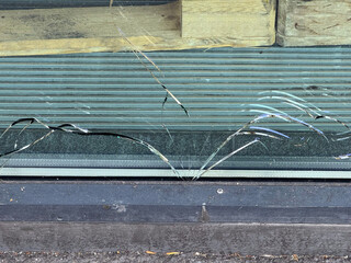 Close-up of bottom of broken shop window with cracks at tram station at Swiss city of Zürich on a...
