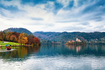 Autumn sunset lake Bled, church of Assumption of Mary Pilgrimage on island, swimming boat in Slovenia