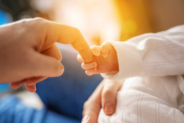 Newborn baby's tiny hand gripping father's finger, capturing a precious moment of bonding and connection