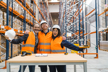 Warehouse workers and manager hugging each other, celebrating successful teamwork and logistics operations in a distribution center