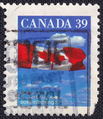 Canadian flag over clouds on a 1992 Canada vintage postage stamp. Canadian flag Series