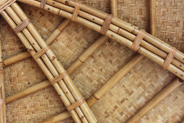 View of a traditional bamboo roof or ceiling, highlighting the intricate craftsmanship. Large, smooth bamboo poles are securely fastened together with natural cordage.