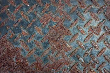 View of a heavily rusted diamond plate metal surface. The textured pattern is visible beneath...