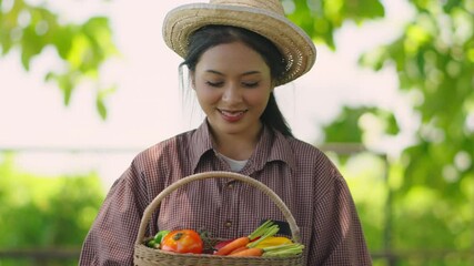 Portrait of Happy Smiling Asian Woman wearing straw hat and plaid shirt holding basket with fresh vegetables, Farming and organic food concept.