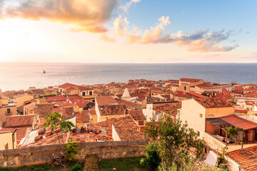 Obraz premium wonderful landscape of beautiful mediterranean sunset town in Italy with orange old tile roofs, nice sea gulf coast, calm evening water and awesome yellow cloudy sky on background