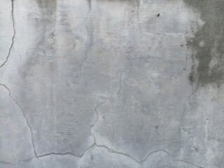 Grey Concrete with Cracks and Stains. A close-up of a weathered grey concrete surface featuring prominent cracks and dark, abstract stains