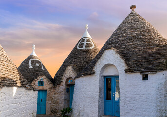 beautiful touristic view of white mediterranean buildings in old medieval Italian style of trulli in Alberobello. Antuque arhitecture in beautiful evening landscape.