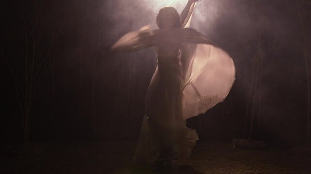 Young woman dancing gracefully in moonlight forest
