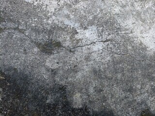 Distressed Grey Concrete Texture. A close-up of a heavily weathered and discolored concrete surface with cracks and dark stains, creating a rugged texture