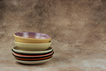 Plates on a textured background. A stack of ceramic plates of different shapes. There is space for text.
