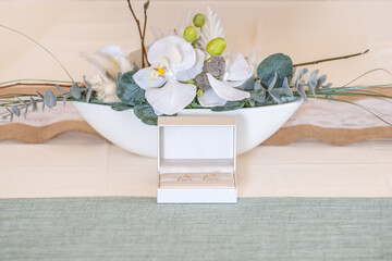 Elegant gold wedding rings lie among soft satin white ribbon. Front vertical view. Mockup for wedding postcard