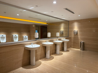 Empty public men restroom, bathroom interior with washing hand sinks. Mirror with hand basin and faucet in clean luxury toilet.