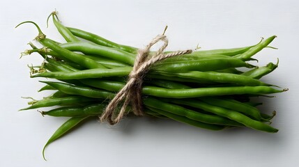 Fototapeta premium A bundle of fresh green beans tied with twine long title A bundle of long vibrant green beans tied together with natural twine on a plain white