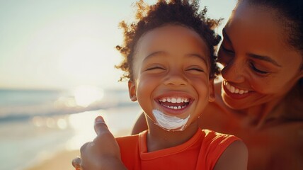 Mother applying sunscreen, laughing with child near ocean waves under bright summer sunshine